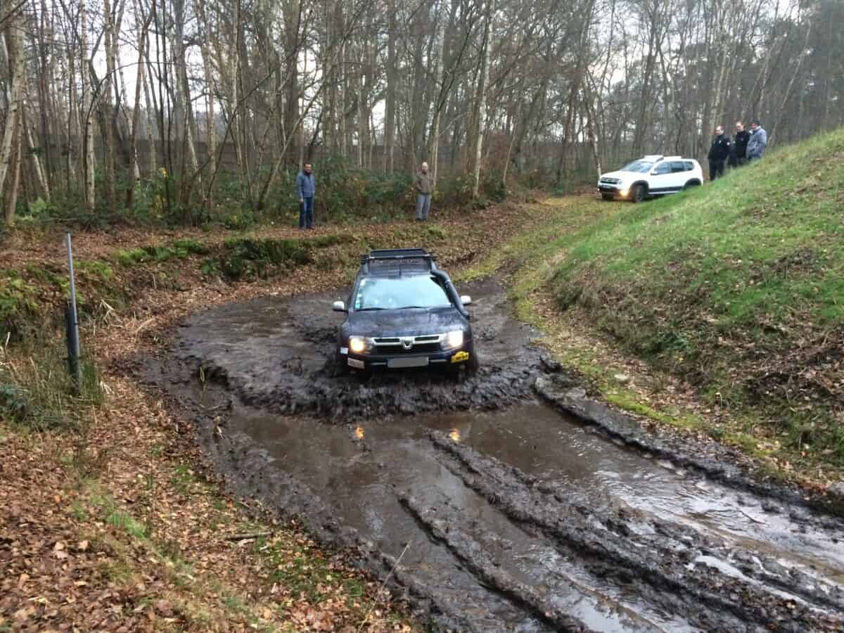 véhicule 4x4 roulant dans une marre de boue et entouré de plusieurs stagiaires