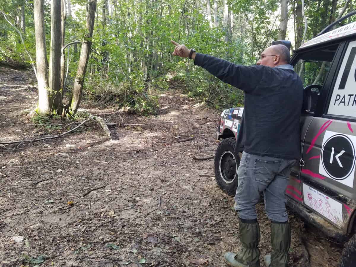 Moniteur de pilotage tout-terrain expliquant à un stagiaire pilote au volant de son véhicule quel chemin il doit emprunter pour un exercice