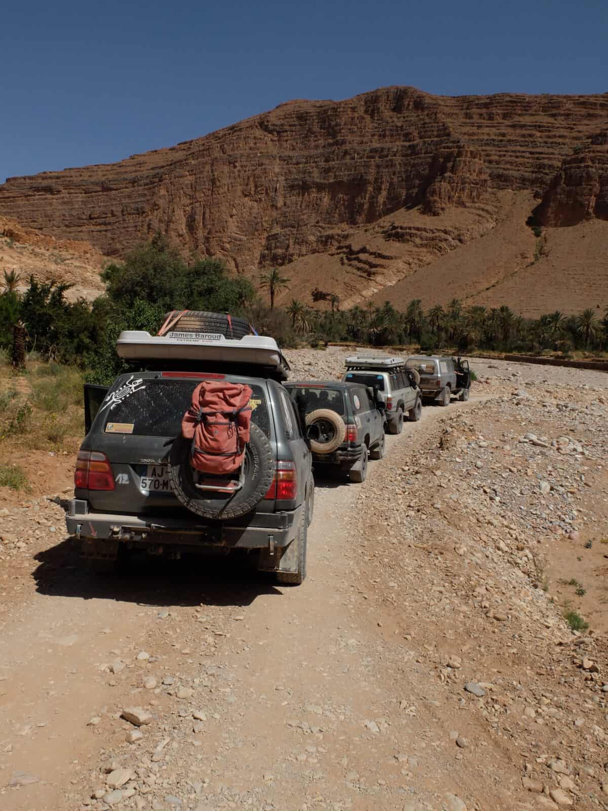 file de véhicules tout-terrain sur une piste rocailleuse dans le désert