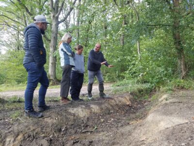 Formateur de conduite 4x4 expliquant à trois stagiaires comment franchir un fossé dans une forêt