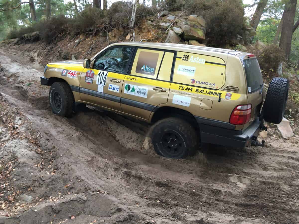 un 4x4 franchi une côte sur un terrain sablonneux accidenté